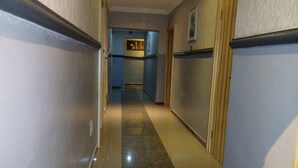 A narrow hallway with a marble floor, wooden doors, and a blue wall with a framed picture. - Euro Lounge and Suites (Ibadan)