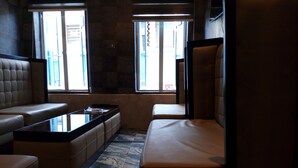 A modern interior with a sofa, a small table, and a bench. There are two windows providing natural light. - Euro Lounge and Suites (Ibadan)