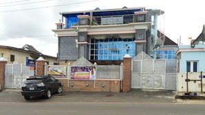 A multi-story building with a gated entrance, a parked car, and a sign advertising live streaming football events. - Euro Lounge and Suites (Ibadan)