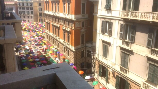 A street lined with colorful umbrellas, historic buildings with balconies, and a clear sky. - Guest House Roma (Genoa)