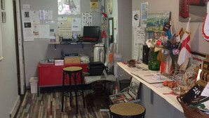 A compact kitchen with a wooden floor, a red cabinet, a laptop, and a small dining area with stools. - Guest House Roma (Genoa)