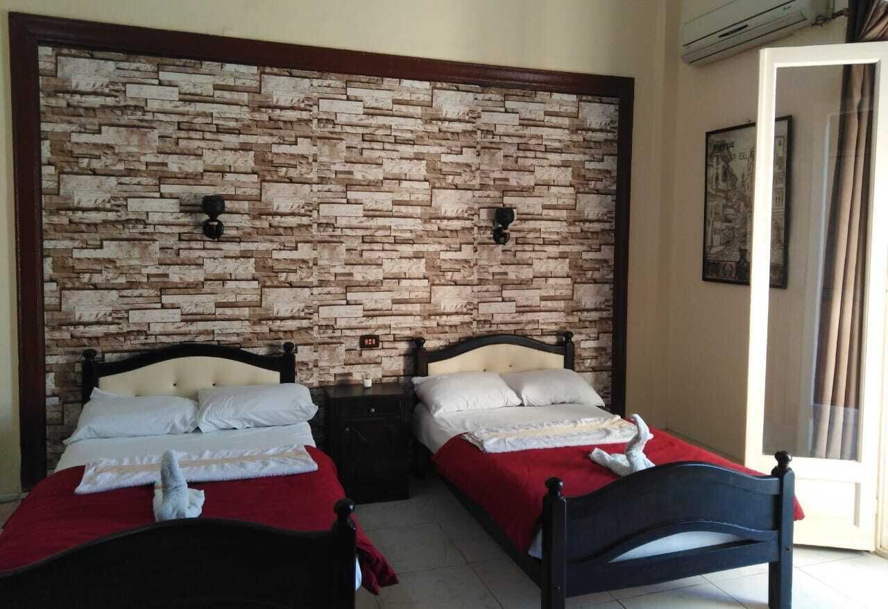 A room with two beds, a stone wall, a nightstand, and a door.