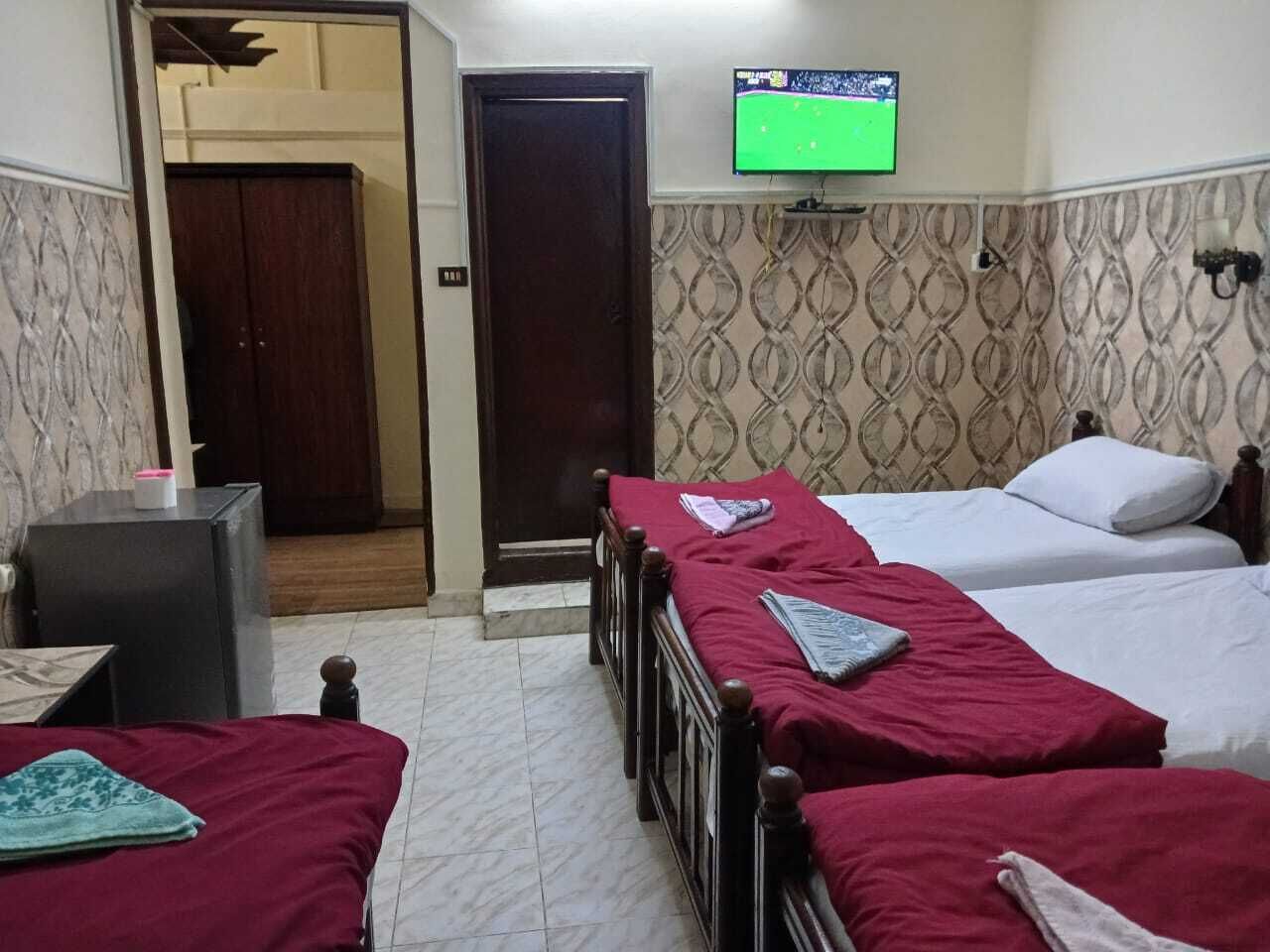 A hotel room with two single beds, a TV on the wall, and a small table with a chair.