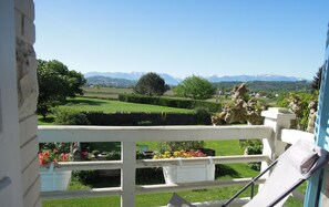 A balcony with a view of a well-maintained garden, a stone statue, and distant mountains. - L'Estancat (Pardies-Pietat)