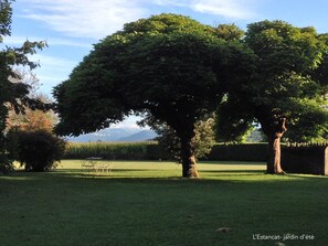 A well-maintained garden with mature trees, a grassy lawn, and a bench. - L'Estancat (Pardies-Pietat)