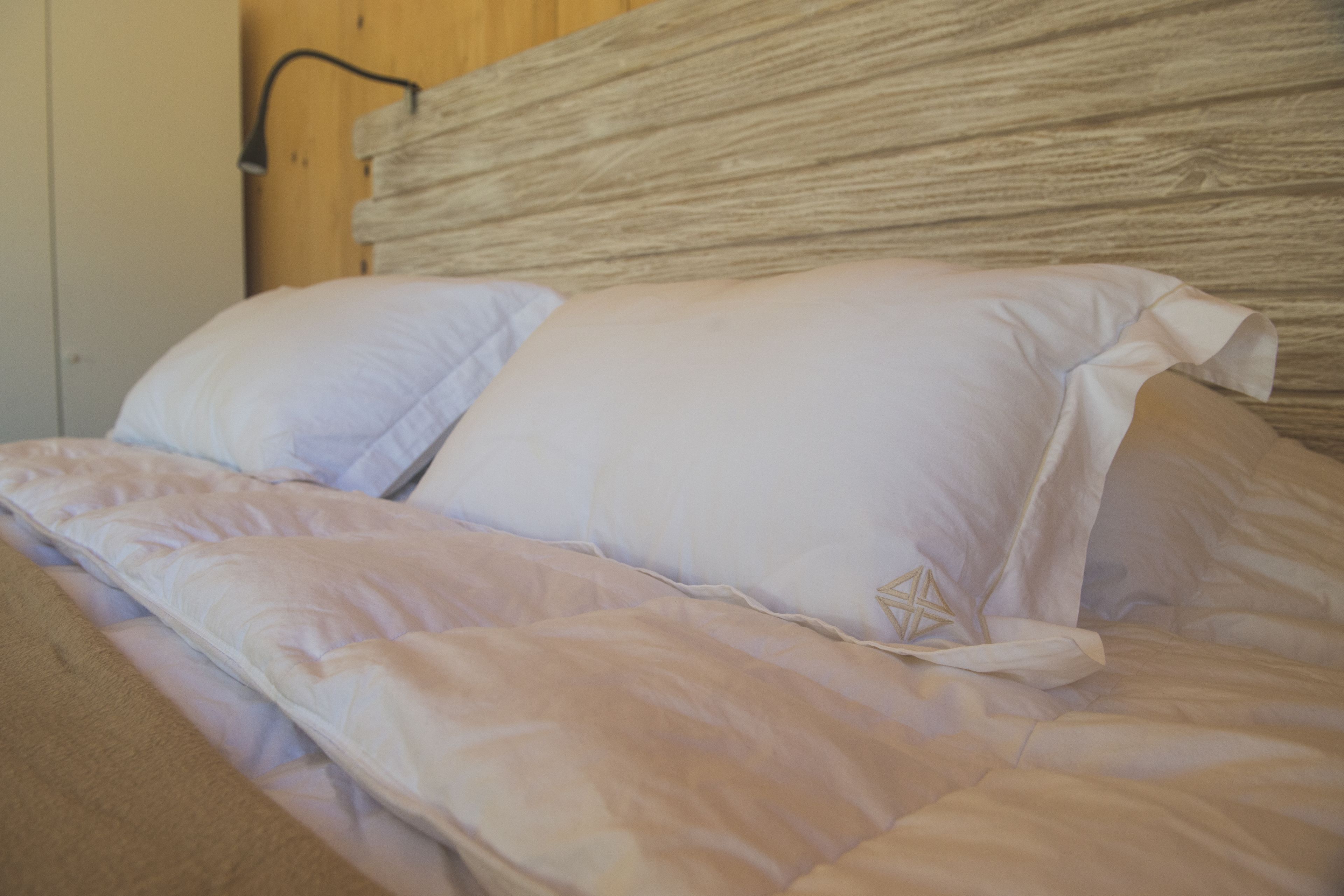 A bed with white bedding and a wooden headboard.