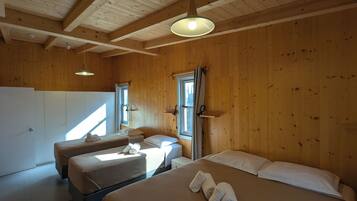 A wooden cabin with two beds, a kitchenette, and a large window.