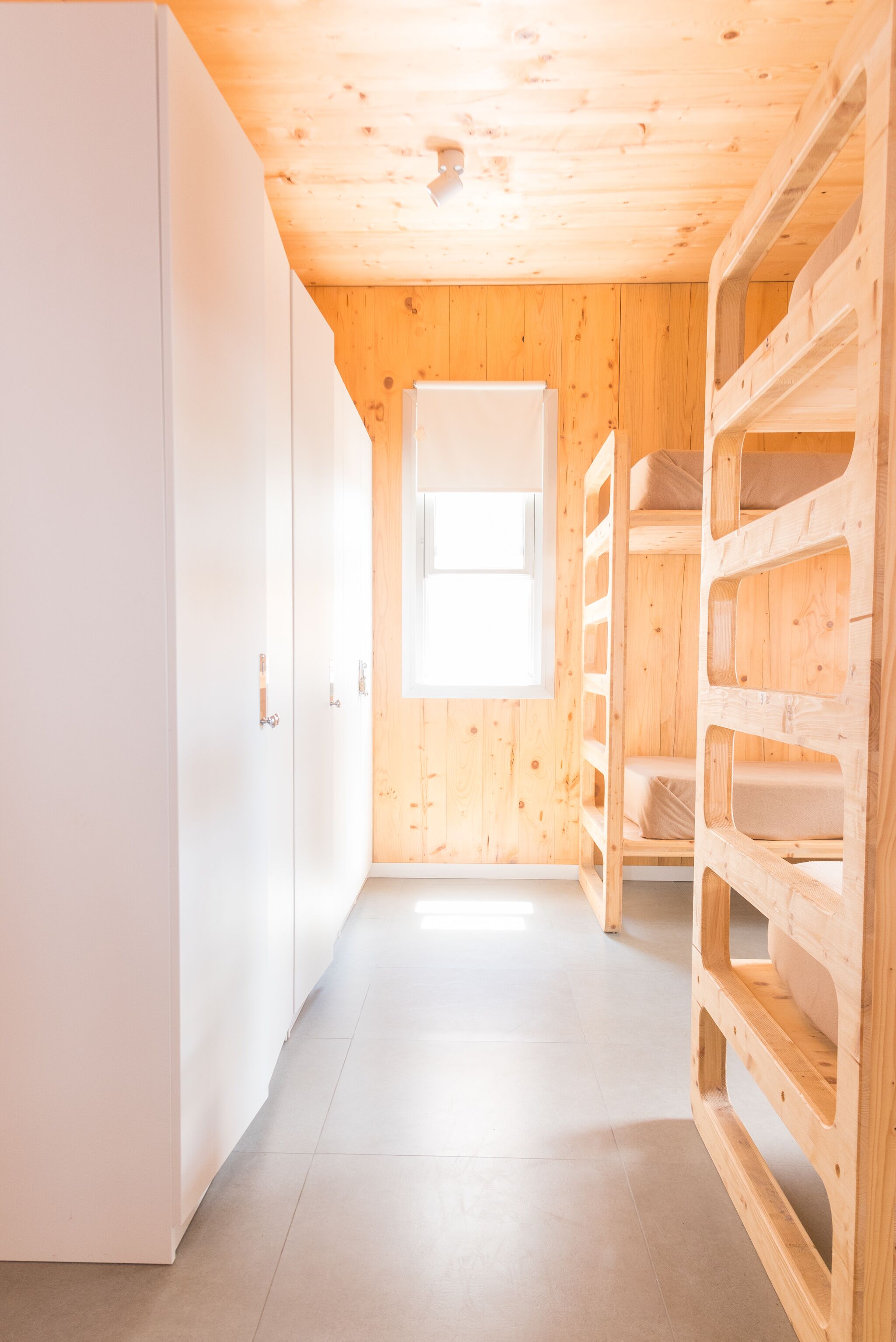 A narrow hallway with wooden walls and a white wardrobe on the left.