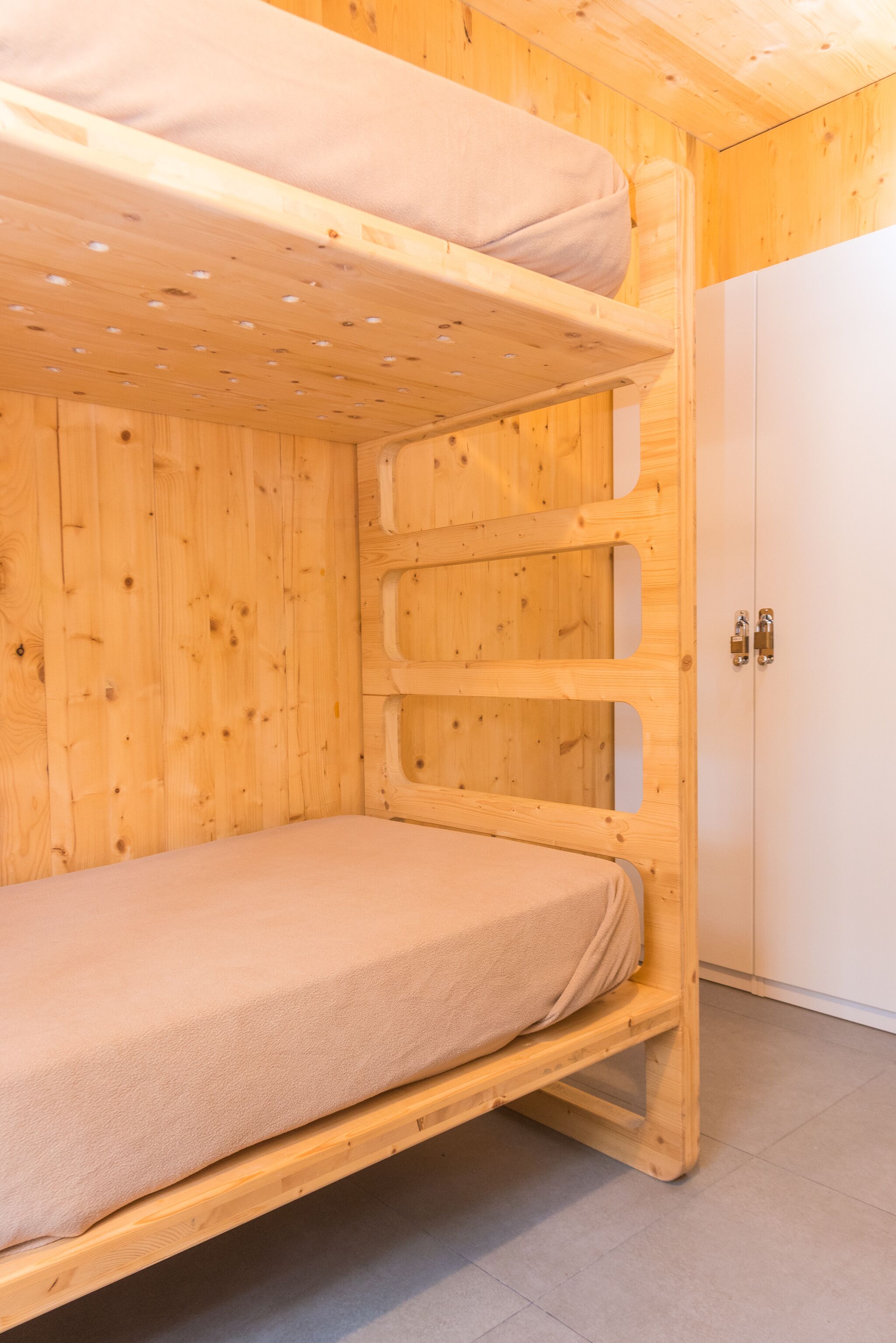 Una cama litera con colchón y cabecera de madera.