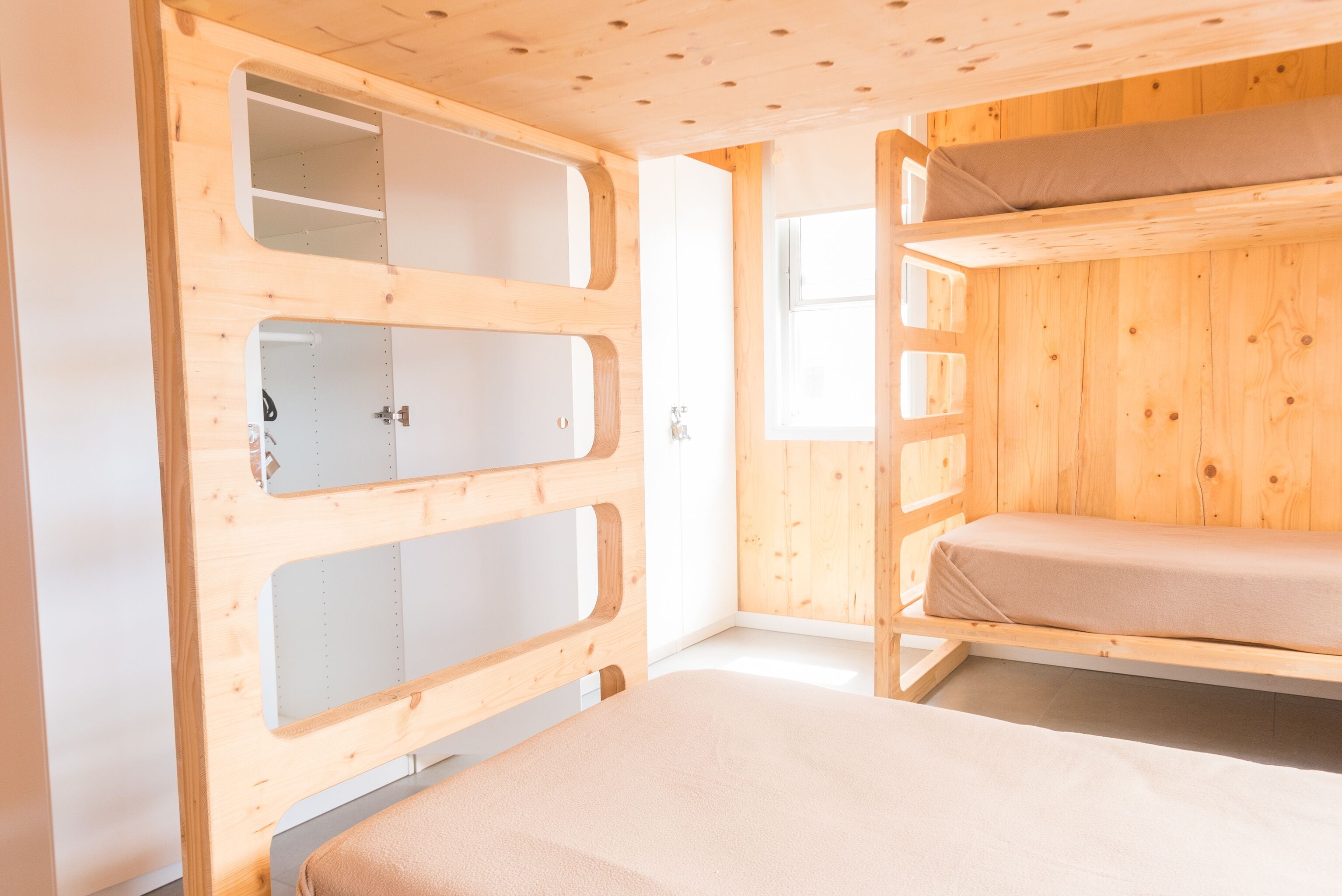 Habitación con literas de madera, una ventana y una puerta.