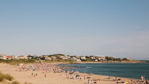 Una spiaggia con persone, edifici e cielo sereno.