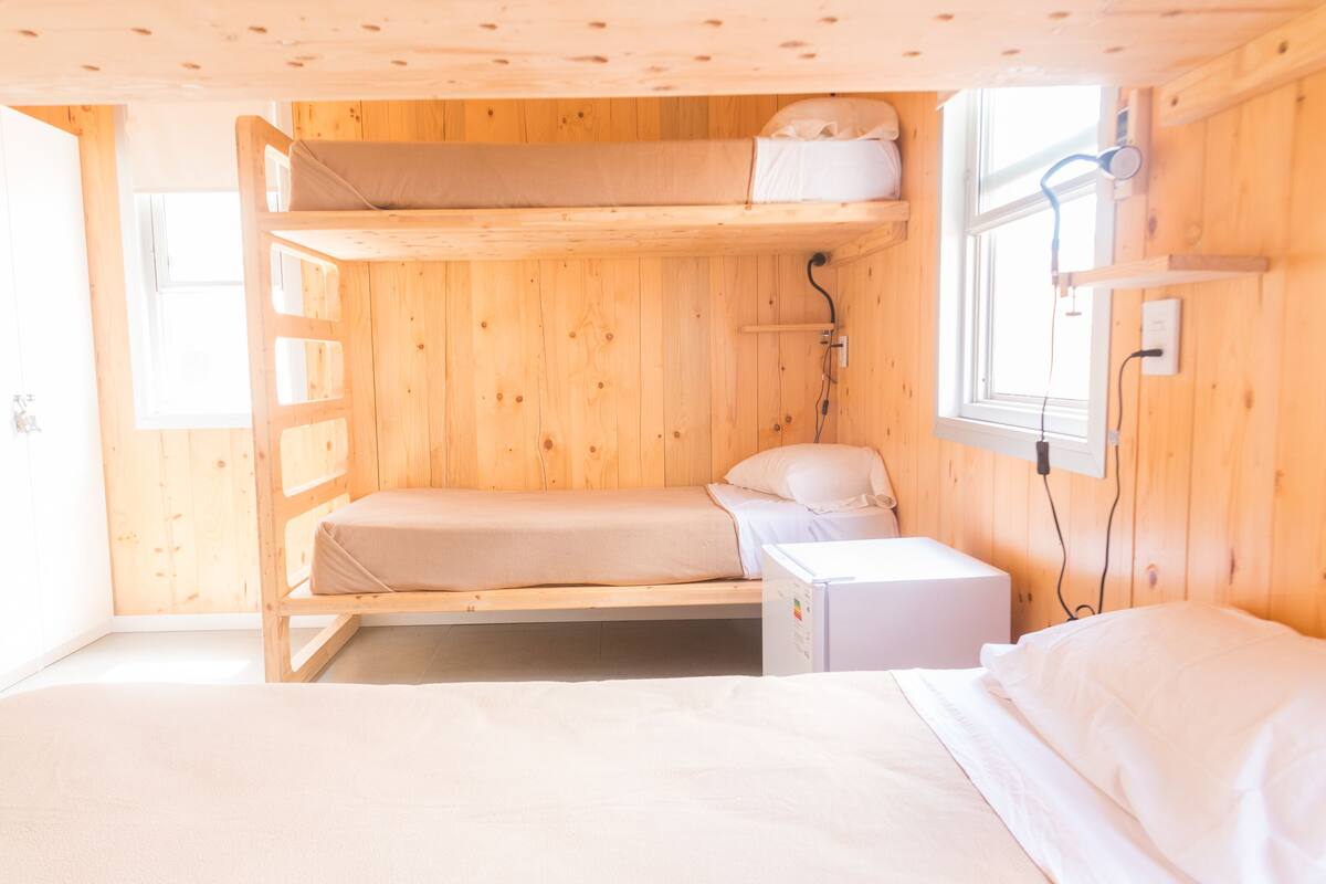 Una stanza in legno con letti a castello, un comodino e una finestra.