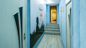 A hallway with a mural of a city skyline, a staircase, and doors on either side.
