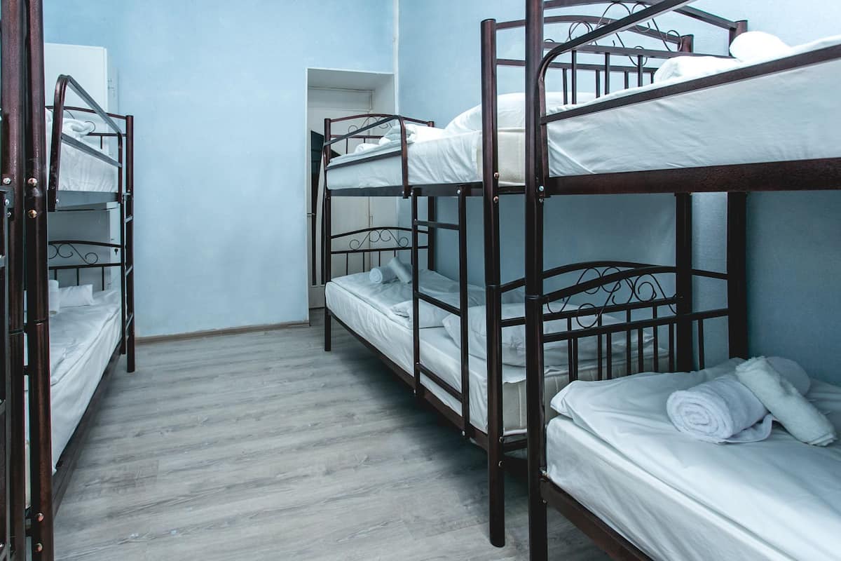 A room with bunk beds, wooden flooring, and light blue walls.