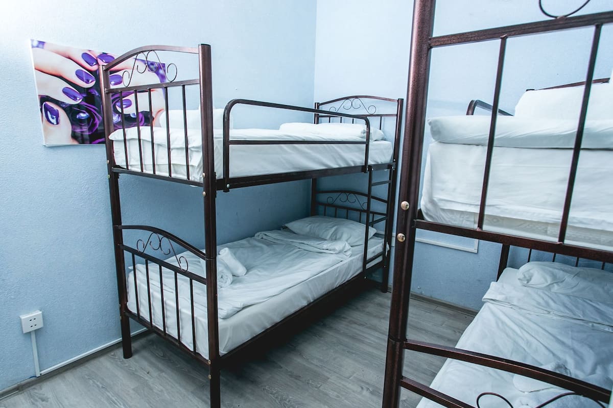 A bunk bed room with a blue wall and a painting of nails.