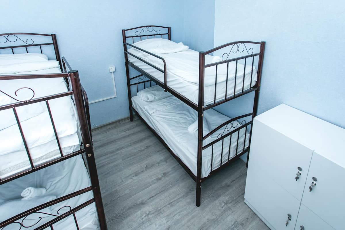 A room with two bunk beds, a white wardrobe, and a light blue wall.