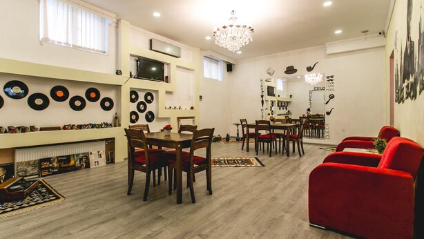A spacious living room with a dining area, wooden flooring, and a red sofa.