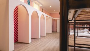 A hotel room with bunk beds, a wooden floor, and a pink wall with a red patterned section.