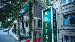 A green sign with "HOSTEL" written on it, indicating a hostel building.