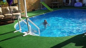 A swimming pool with a slide and artificial turf surrounding it. - Tudor House (Wisbech)