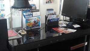 A reception desk with a clock, posters, a computer, and various brochures. - Tudor House (Wisbech)