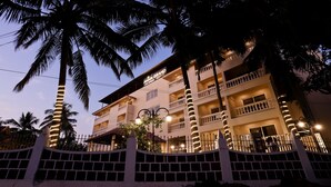 A multi-story hotel with balconies, palm trees, and a well-lit facade. - Amara Grand Baga (Baga)