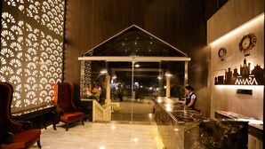 A hotel lobby with a reception desk, seating area, and decorative wall panels. - Amara Grand Baga (Baga)