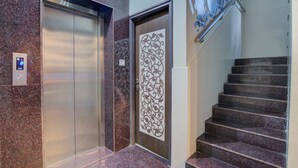 An elevator, a decorative door, and a staircase with a handrail. - OYO 11916 Varcity Plaza (Bengaluru)