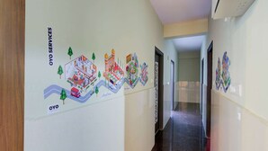 A hallway with a mural depicting a cityscape and a sign that reads "OYO SERVICES". - OYO 11916 Varcity Plaza (Bengaluru)