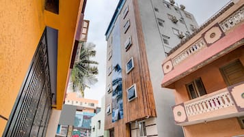A narrow street with multi-story buildings, including a building with a wooden facade and balconies.