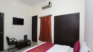 A hotel room with a bed, a desk, a chair, a TV, and a wardrobe. - OYO 12868 Hotel City Lite (New Delhi)