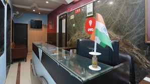 A hotel reception area with a glass counter, a flag, a clock, and an elevator. - OYO 12868 Hotel City Lite (New Delhi)
