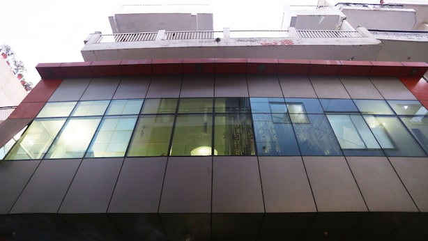 A modern building with large glass windows and a red and grey facade. - OYO 12868 Hotel City Lite (New Delhi)