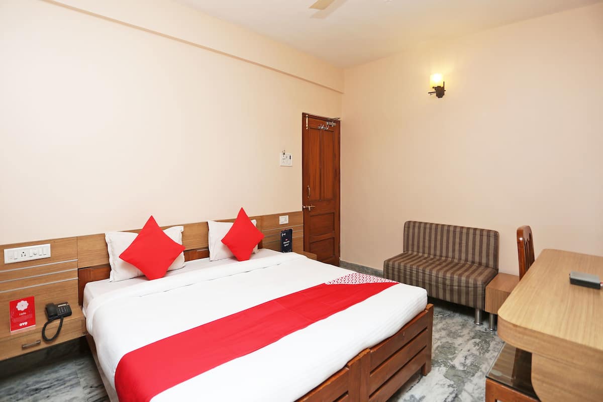 A hotel room with a bed, a desk, a chair, a wardrobe, and a ceiling fan.