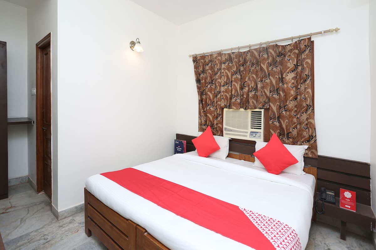 A hotel room with a bed, a nightstand, a telephone, and a wall-mounted air conditioner.