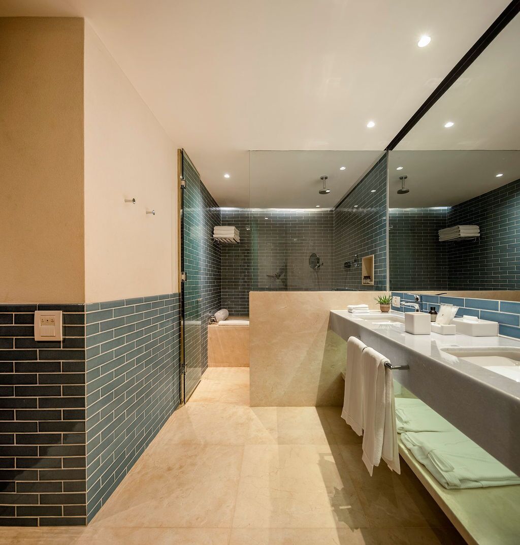 A modern bathroom with a large mirror, two sinks, and a shower area.