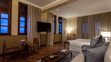 Una habitación de hotel con una cama, televisión, escritorio y una silla.