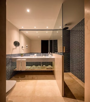 Un baño moderno con un espejo grande, un lavamanos y una zona de ducha.