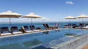 A poolside area with lounge chairs and umbrellas, overlooking the ocean. - Hotel Fasano Salvador (Salvador)