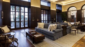 A spacious living room with a large grey sofa, a wooden coffee table, and wicker chairs. - Hotel Fasano Salvador (Salvador)