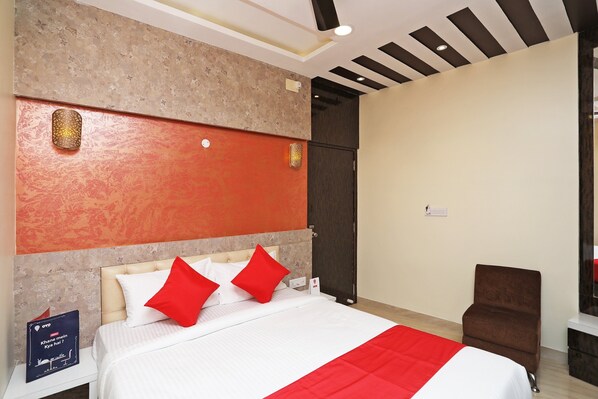 A hotel room with a bed, a nightstand, a chair, and a door.