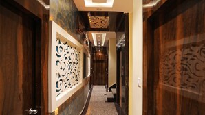 A hallway with wooden doors, a decorative wall panel, and a carpeted floor. - OYO 15617 Abi's Inn (Kolkata)