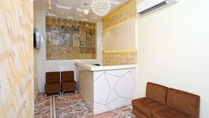 A reception area with a marble floor, a reception desk, two brown sofas, and a wall with a mosaic design. - OYO 15617 Abi's Inn (Kolkata)
