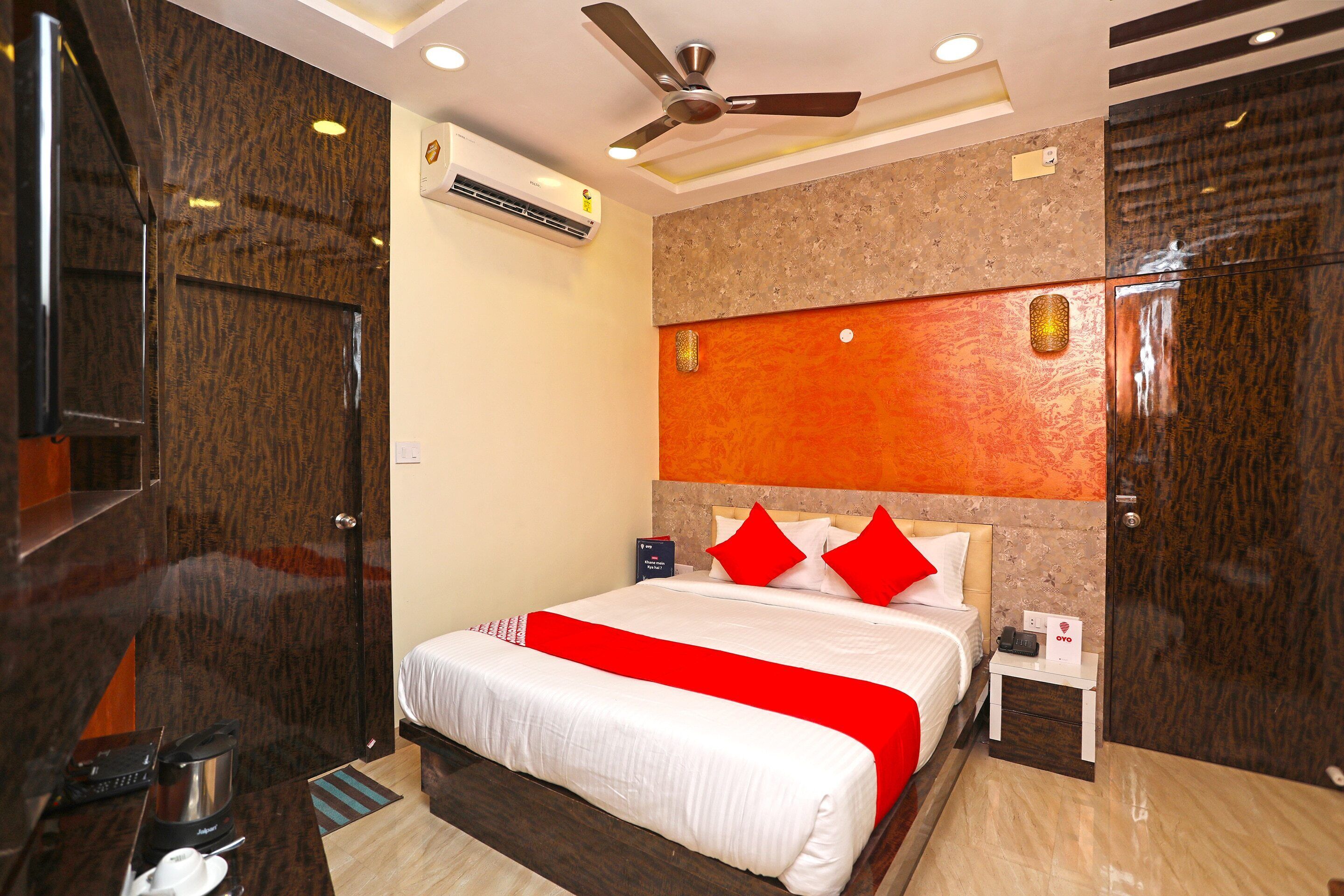 A hotel room with a bed, a nightstand, a coffee maker, and a ceiling fan.