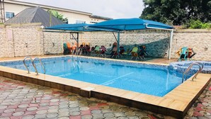 A rectangular swimming pool with a tiled edge, surrounded by a patterned walkway. - Feligold Royal Hotel Benin (Benin City)