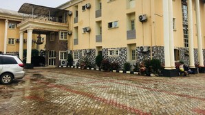 A multi-story building with a central entrance, air conditioning units, and a paved courtyard. - Feligold Royal Hotel Benin (Benin City)