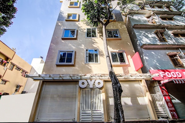 A building with a closed shutter, a sign reading "OYO", and a red sign with "FOOD" visible.