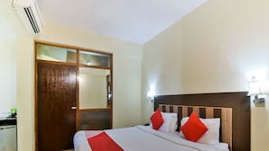 Une chambre d’hôtel avec un lit, une table de chevet en bois, un bureau et une armoire.
