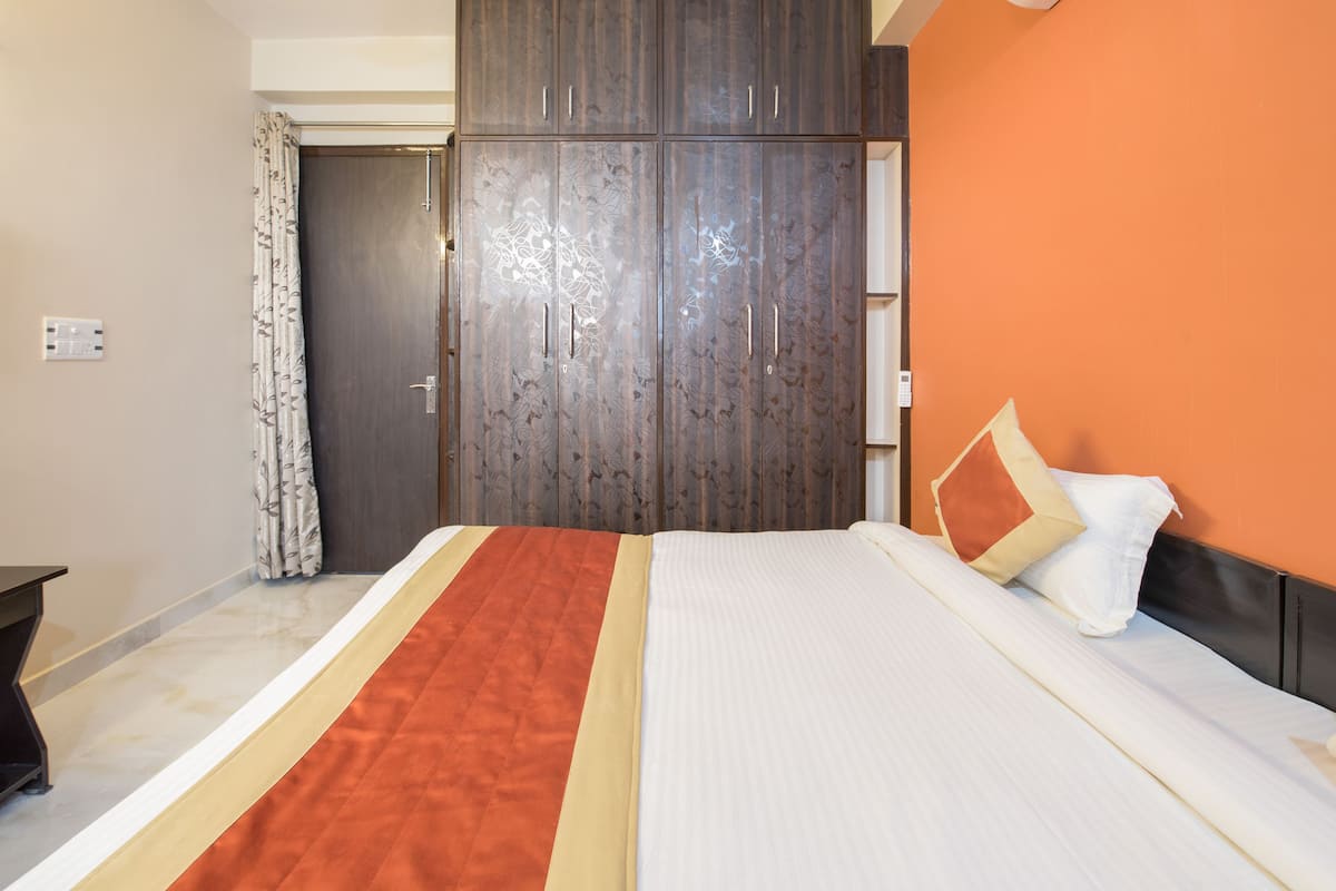Ein Schlafzimmer mit einem großen Bett, einem Kleiderschrank und einer orangefarbenen Wand.