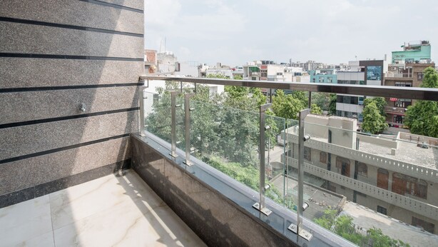 Un balcon offrant une vue sur le paysage urbain, avec des bâtiments et des arbres.